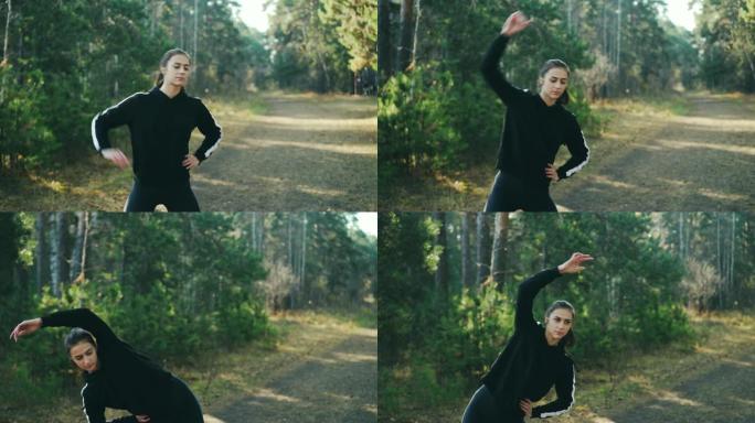 穿着现代运动服的漂亮黑发女人独自在公园里锻炼，弯曲和移动手臂和身体，享受新鲜空气、体育活动和自然。