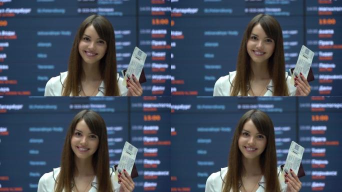 美丽的俄罗斯旅客在机场对着相机微笑，同时拿着护照和登机牌
