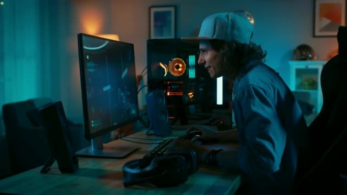 专业玩家在他强大的个人电脑上玩第一人称射击游戏在线视频游戏。房间和电脑有彩色霓虹灯。年轻人戴着帽子。