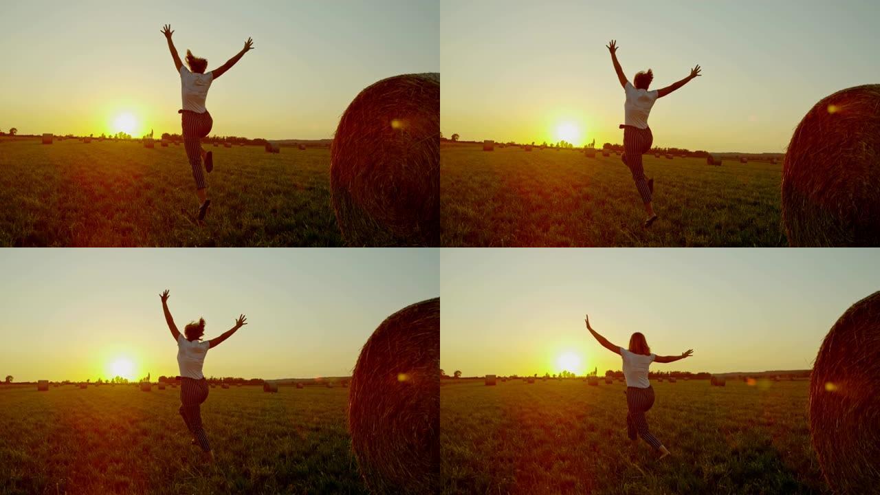 慢动作，女士无忧无虑的女人在日落时分带着干草在田园诗般的乡村田野中跳跃