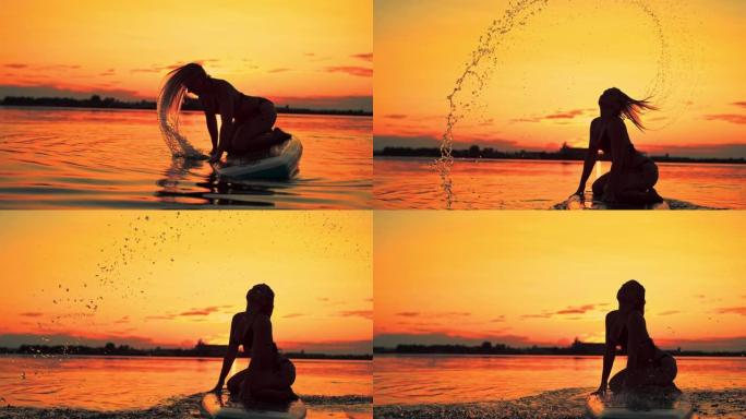 一个女性冲浪者在黄昏时翻转湿头发的超级SLO MO剪影