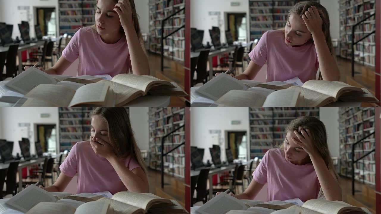 美丽的年轻女学生在图书馆看书打哈欠