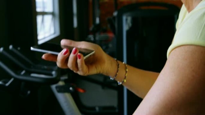 健身工作室4k运动时用手机聊天的高级女性
