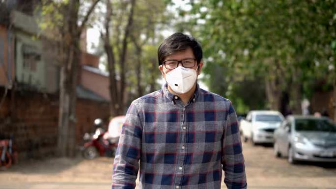 戴空气污染面具的亚洲男子在城市行走的前视图泰国清迈