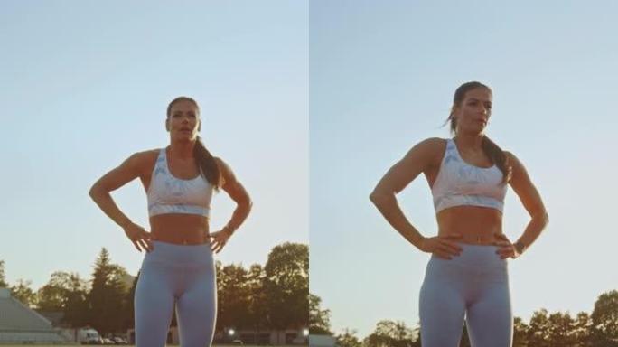 穿着浅蓝色运动上衣和紧身裤的美丽健身女子屏住呼吸，在体育场摆姿势。垂直屏幕方向视频9:16