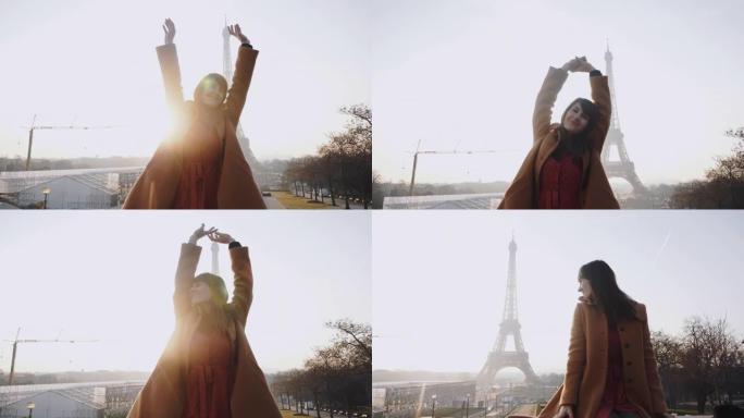 美丽快乐微笑的旅游女人的肖像坐着，在巴黎埃菲尔铁塔日出时举手慢动作。
