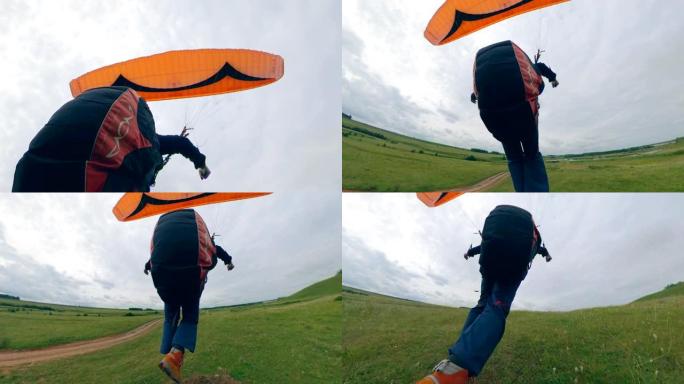 一个人带着滑翔伞飞行后降落在田野上。