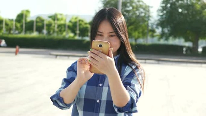年轻的亚洲妇女在城市街道上使用手机