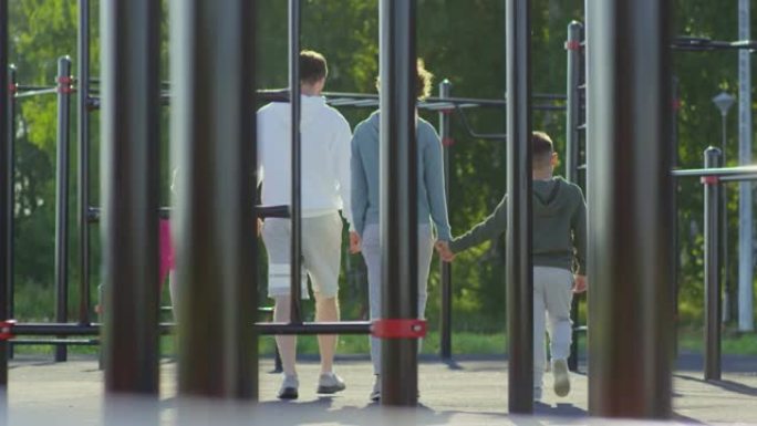 运动父母与孩子们在户外健身操场上散步