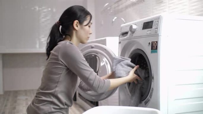 年轻的亚洲妇女在家洗衣服