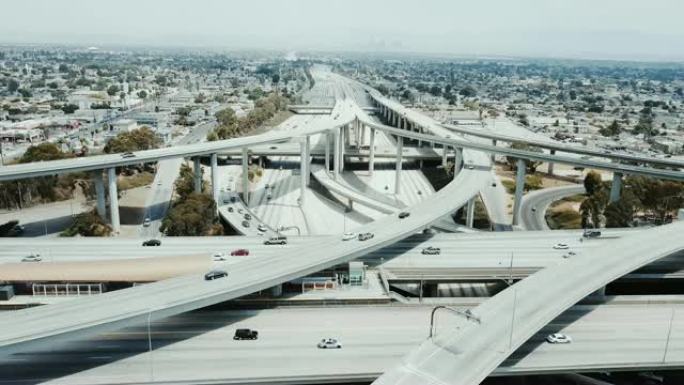 无人机在洛杉矶巨大的高速公路交叉口上向后移动，汽车穿过许多路口和桥梁。