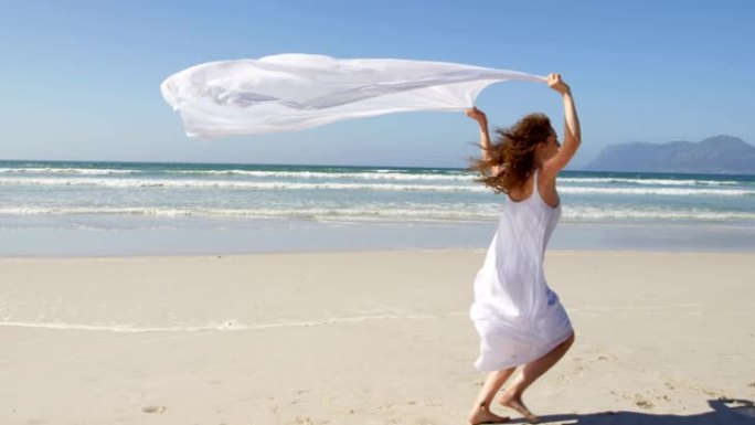 女人在海边奔跑，戴着等待的围巾。在海滩4k