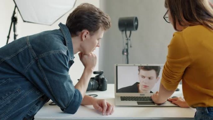 模特和摄影师在工作室的笔记本电脑上观看照片的慢动作