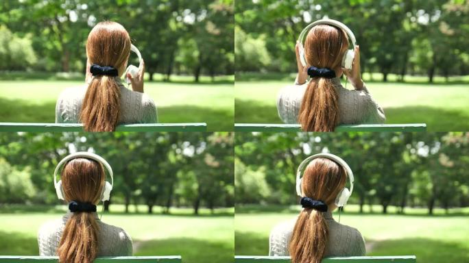 公园里戴着耳机的年轻迷人女人
