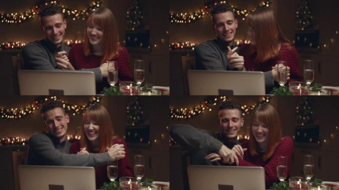 一对年轻夫妇在圣诞节晚上在电脑上浏览照片。他们玩，放纵，玩得开心。