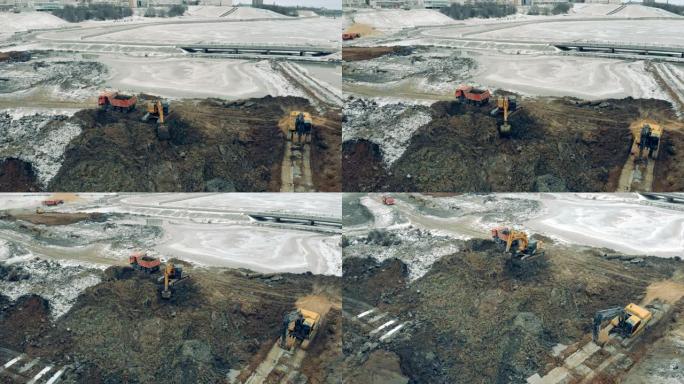 挖掘机和卡车工作的建筑工地上方的鸟瞰图。机器在一个很大的职业生涯中工作。