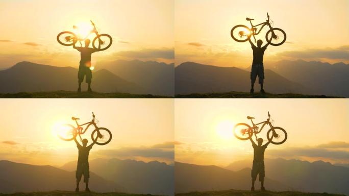 剪影: 男性游客在日出时骑自行车上山后将自行车举到头顶