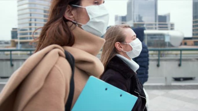 疫情控制社工。检疫期间，两名戴着口罩的白人年轻女医生走在城市街道上。