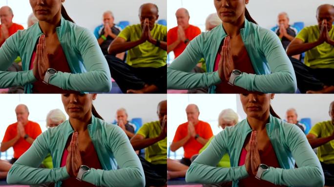 活跃的混血老年人的前视图，教练在4k健身工作室表演瑜伽