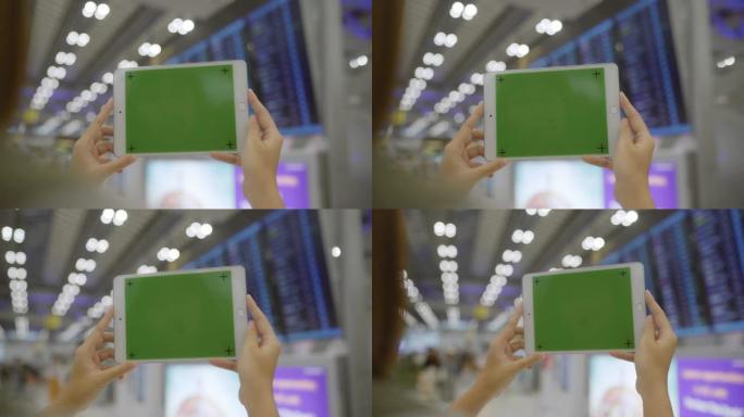 亚洲妇女在国际机场登机口等待航班时，在航站楼大厅使用带有绿色屏幕的白色移动平板电脑设备。