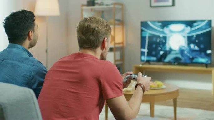 在客厅里，两个朋友坐在沙发上，拿着控制器玩竞争性视频游戏，电视屏幕上显示了3D动作射击游戏。他们在完