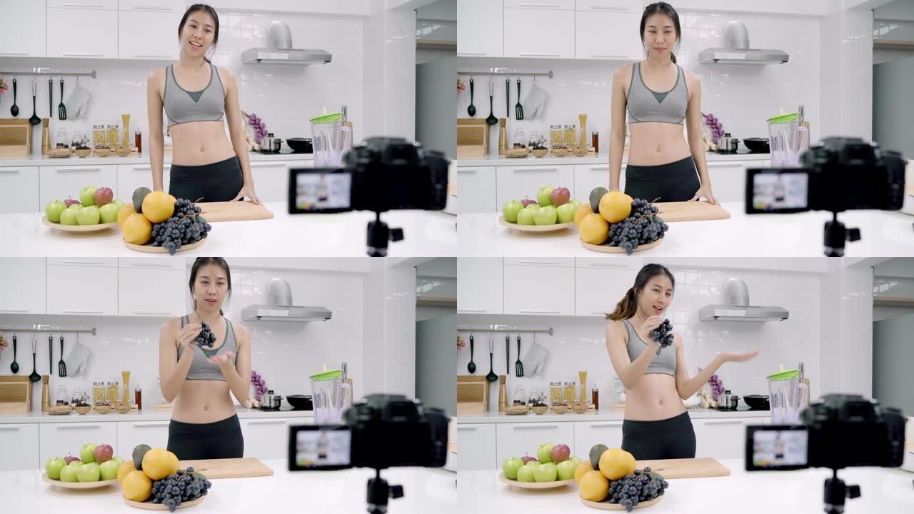 博主运动的亚洲女性使用相机录制如何为订户制作葡萄汁视频，女性使用有机水果自己在家制作葡萄汁。健康食品
