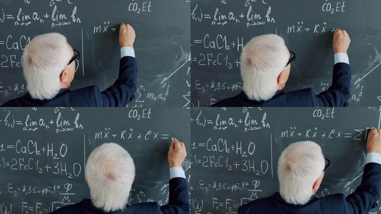 聪明的资深教授在课堂上在黑板上写方程的后视图