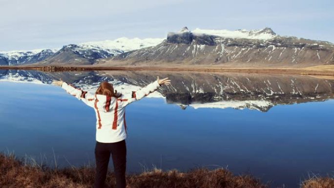 WS无忧无虑的女人站在冰岛阳光明媚的山湖，双臂伸出
