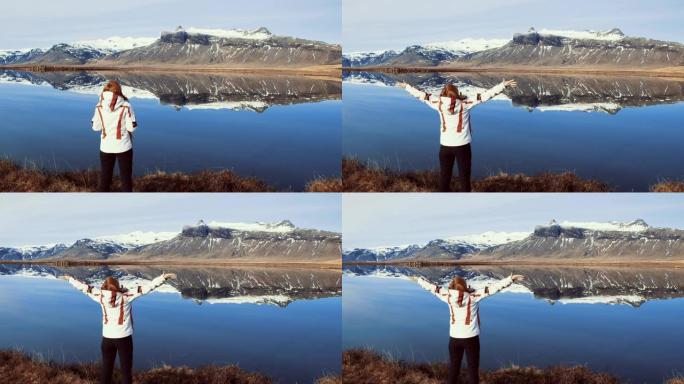 WS无忧无虑的女人站在冰岛阳光明媚的山湖，双臂伸出