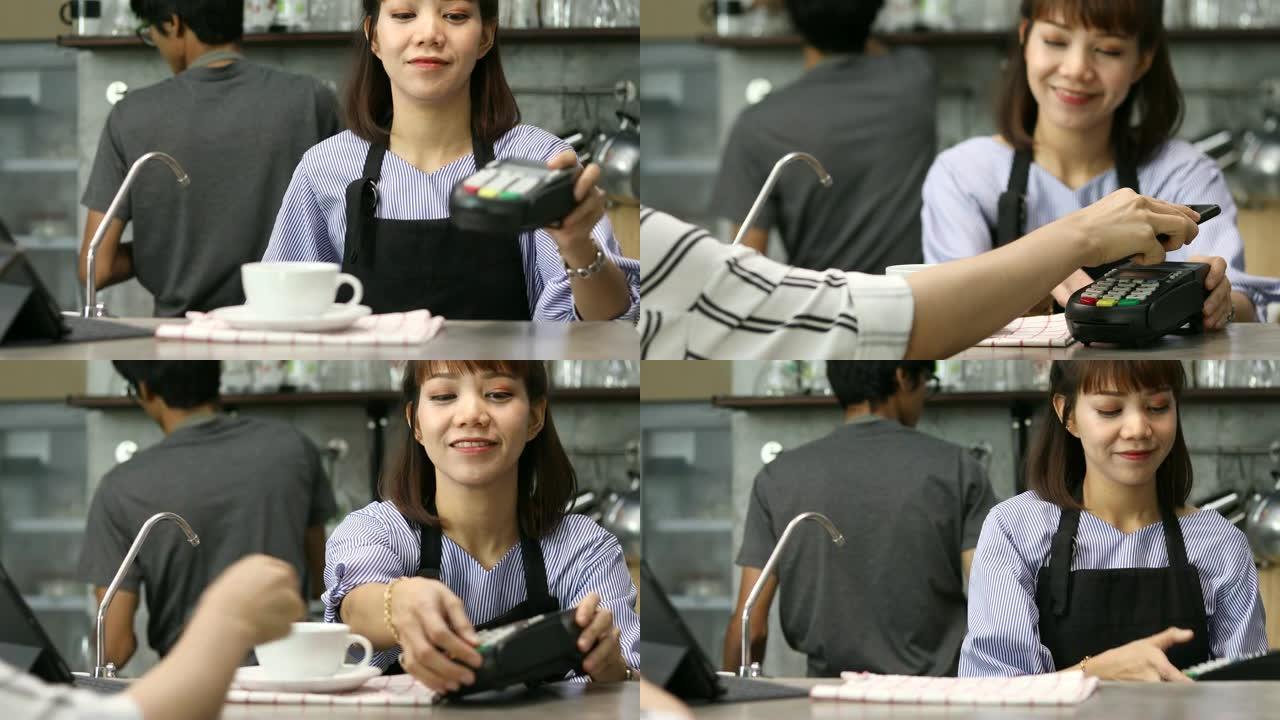 咖啡店的顾客用卡片支付微笑的女服务员
