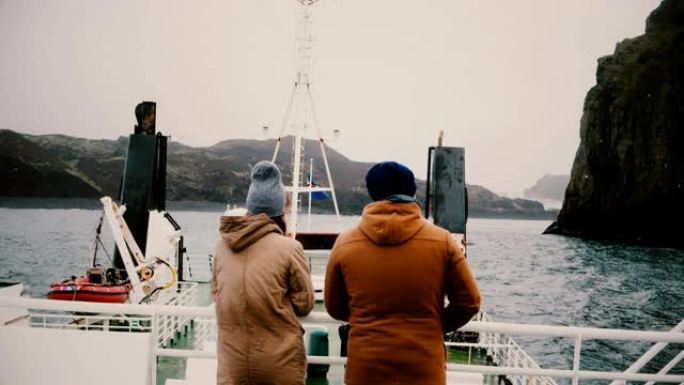 男人和女人站在船上，欣赏美丽的风景，交谈。探索冰岛的游客。