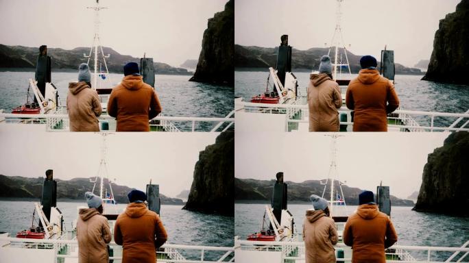 男人和女人站在船上，欣赏美丽的风景，交谈。探索冰岛的游客。