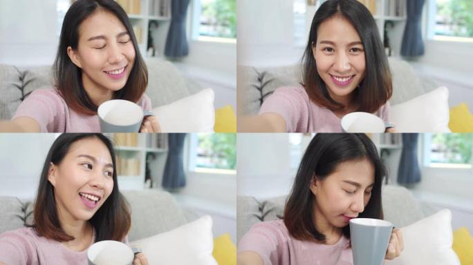 年轻的亚洲青少年妇女在家中vlog，女性喝咖啡并使用智能手机在客厅的社交媒体上制作vlog视频。生活