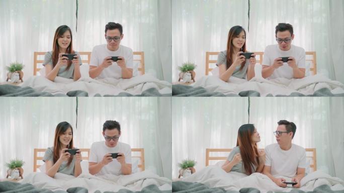 亚洲夫妇使用智能手机并在手机上玩游戏，早上在床上玩得开心。女人获胜并庆祝。