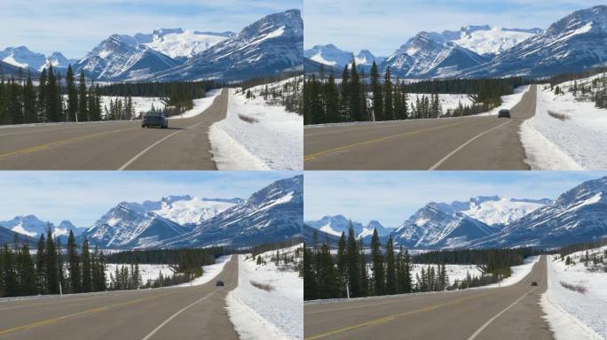 蓝色汽车沿着通往白雪皑皑的加拿大落基山脉的正确道路行驶。