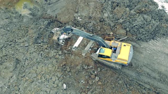 黄色建筑挖掘机在采石场移动重岩石。