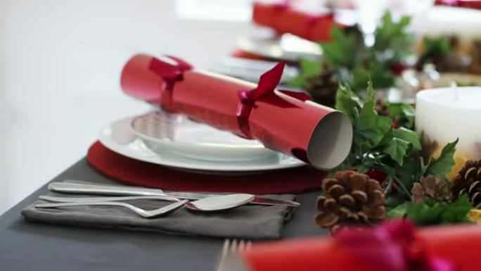 特写镜头，手持镜头显示装饰好的圣诞餐桌上的位置设置，红色圣诞饼干排列在盘子上