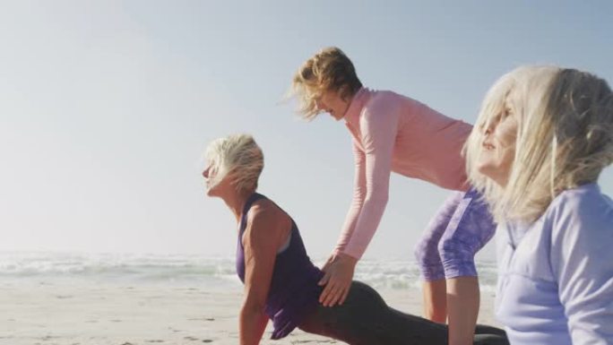 瑜伽老师在海滩上向高级女性教授瑜伽