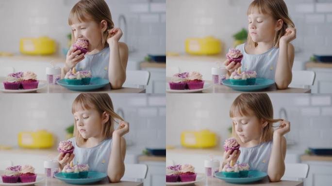 在厨房里: 可爱的小女孩吃奶油蛋糕，糖霜和洒满Funfetti。可爱的饥饿的甜食孩子咬成松饼，含糖糖