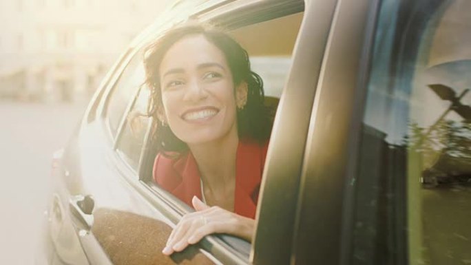 快乐美丽的女人坐在汽车后座上，惊奇地看着窗外。旅行女孩体验世界的魔法。从车外拍摄的相机。