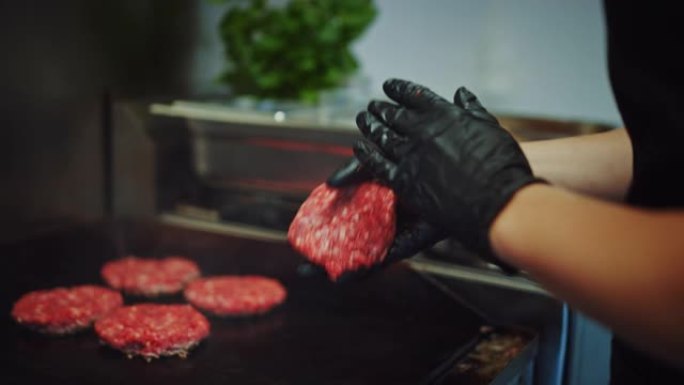在烤架上准备肉饼的美味特写镜头。新鲜的碎牛肉被放在热气或电烤架上。库克正在用新鲜的碎肉制成汉堡肉饼。