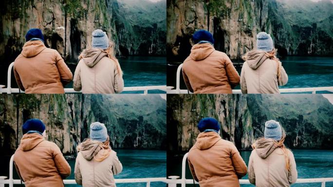 年轻的时尚夫妇站在船上，看着冰岛路过的岛屿。