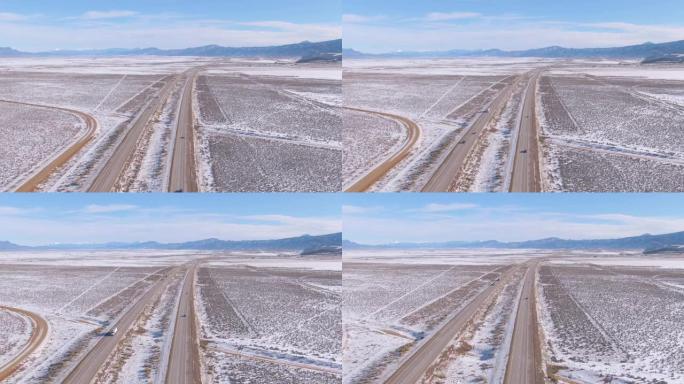 航拍图:在柏油路上飞行，引导车辆穿越白雪皑皑的沙漠