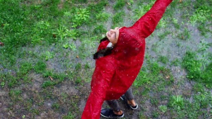 一个快乐的女人在雨中微笑，女人沉浸在快乐自由的雨中慢动作下的舞蹈中。