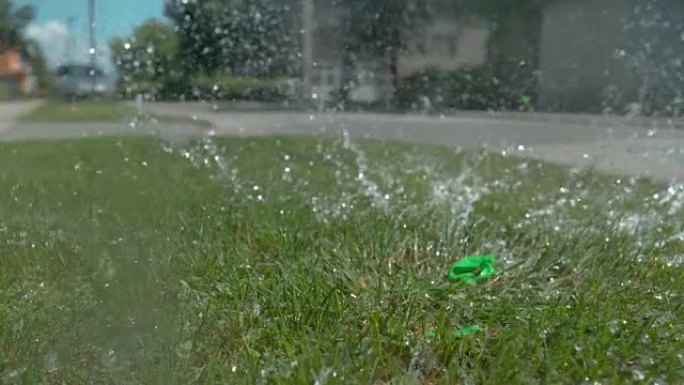 特写: 绿水气球落在草地上后爆炸。