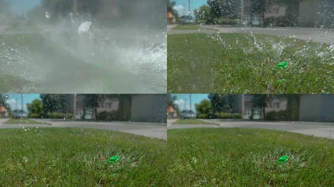 特写: 绿水气球落在草地上后爆炸。
