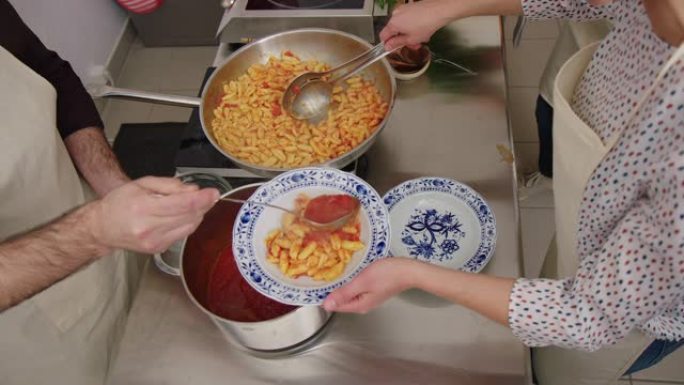 两名厨师在盘子里供应新鲜烹制的意大利面