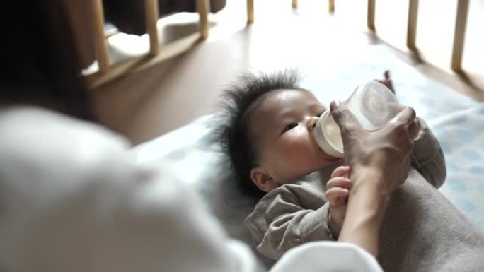 母亲在家用奶瓶喂养亚洲男婴，给新生婴儿喂奶