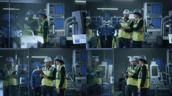现代工厂: 男女工程师穿着安全夹克，站在工业车间的安全帽，说话和使用平板电脑。拥有数控机械、机械臂生