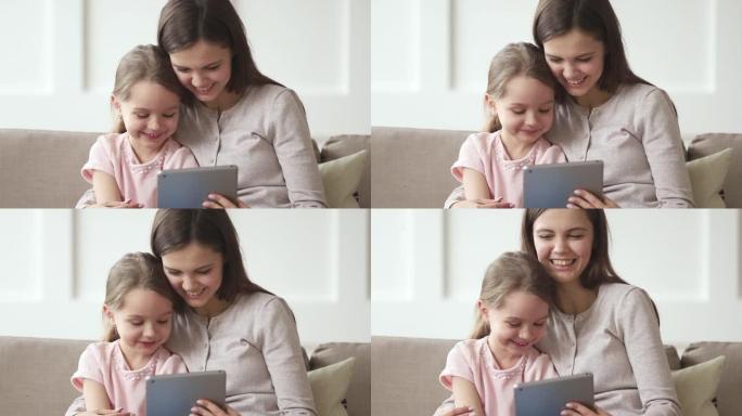 快乐的妈妈和小女儿在平板电脑上看有趣的卡通